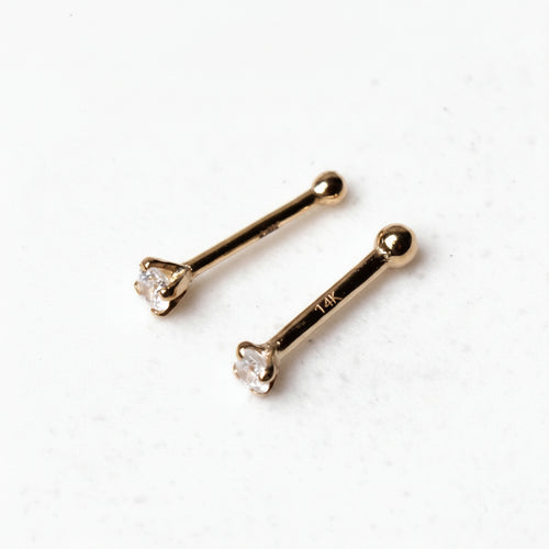 Two gold nose rings with clear gemstones on a white background